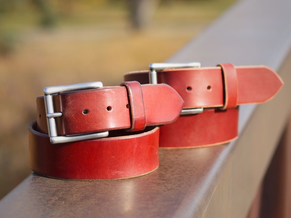 Chestnut full-grain leather belt laid flat on wood — The Man Belt handcrafted by Stewart Leather in Northern Alberta, buy once wear for life