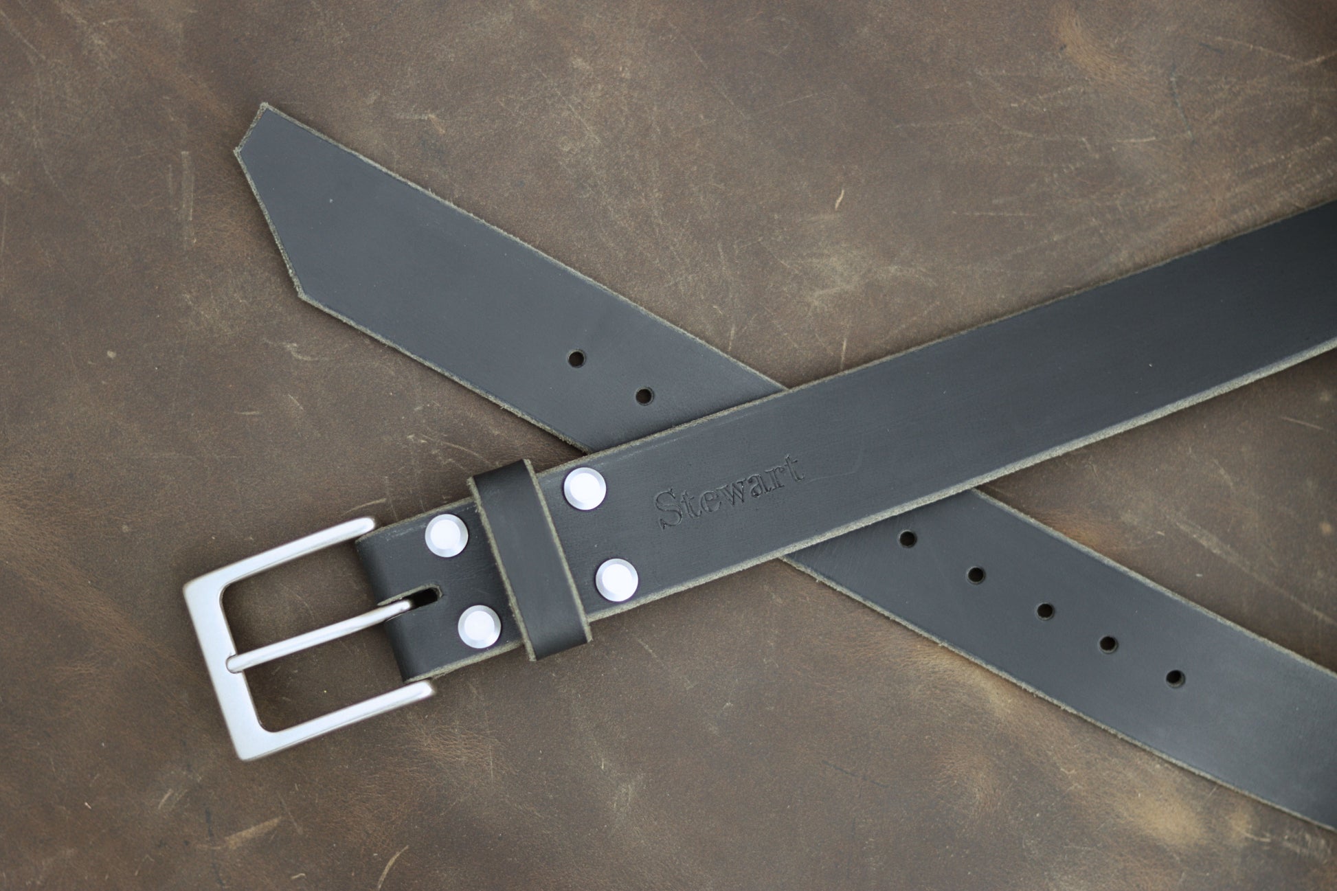 Gray leather belt with silver buckle on a brown leather background