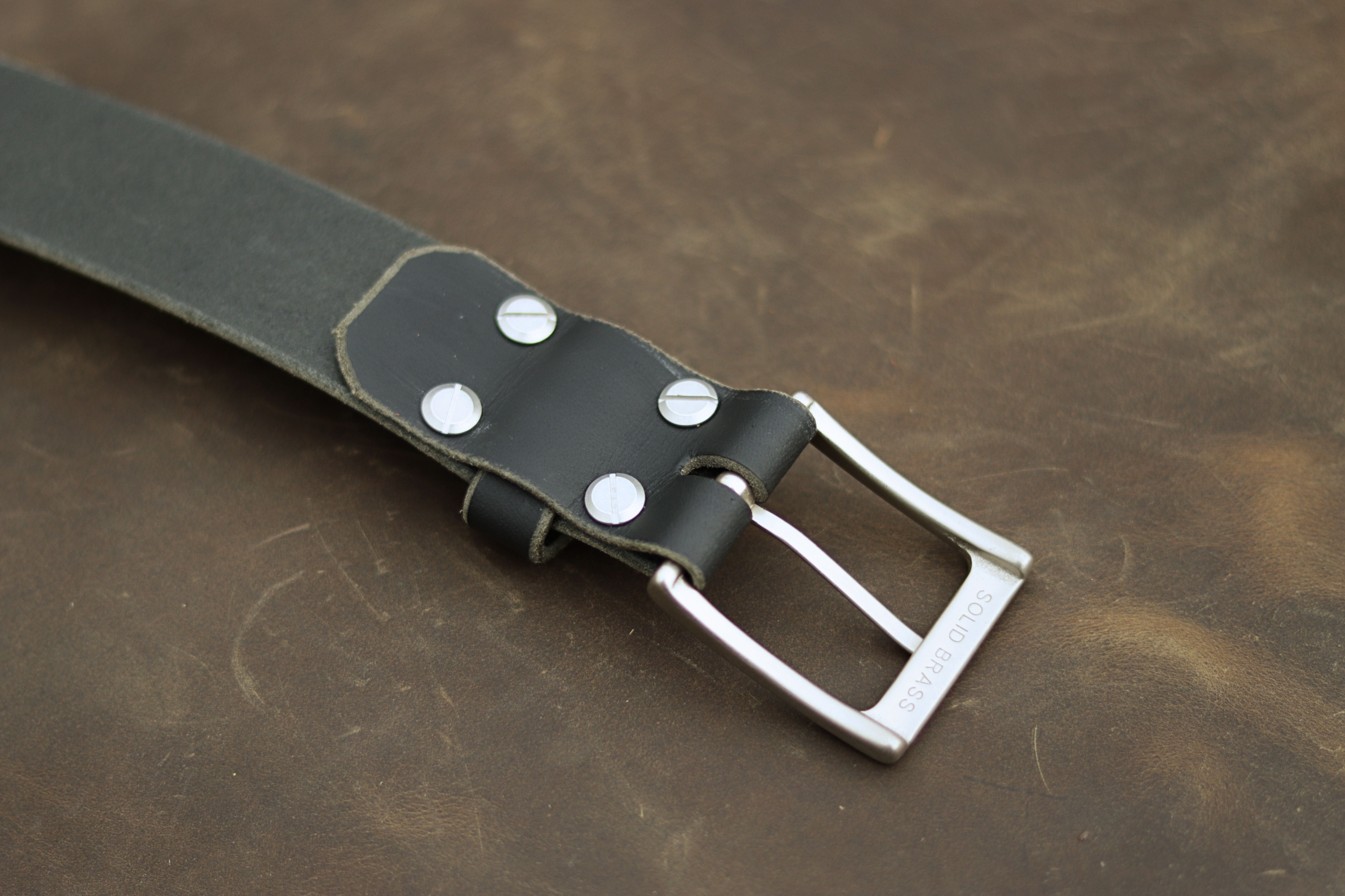 Black leather belt with silver buckle on a brown leather background