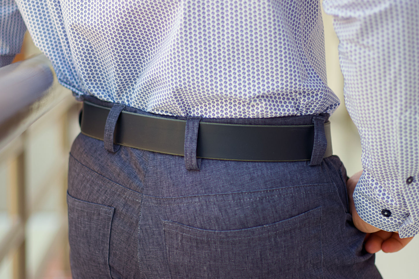 Person wearing a patterned shirt, dark belt, and gray pants.